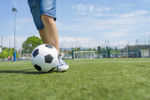 Tiefschnitt eines Jungen, der auf einem Feld gegen den Himmel Fußball übt - CAVF50551