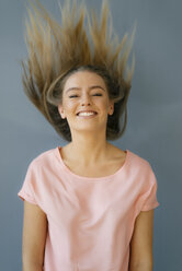 Portrait of smiling young woman tossing her hair - KNSF05002