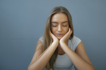 Portrait of young woman with eyes closed and head in hands relaxing - KNSF05013