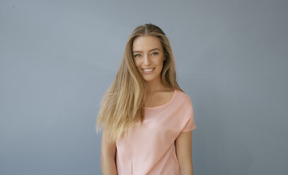 Portrait of smiling woman wearing peach color T-shirt against white  background stock photo