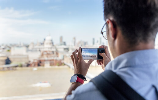 UK, London, Mann fotografiert die Stadt von der Dachterrasse aus - MGOF03803