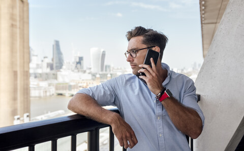 UK, London, Mann am Telefon auf einer Dachterrasse, lizenzfreies Stockfoto