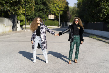 Portrait of fashionable twin sisters holding hands - GIOF04725