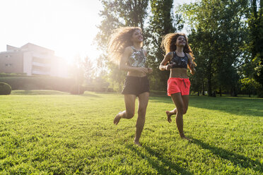 Zwillingsschwestern joggen barfuß auf einer Wiese - GIOF04743