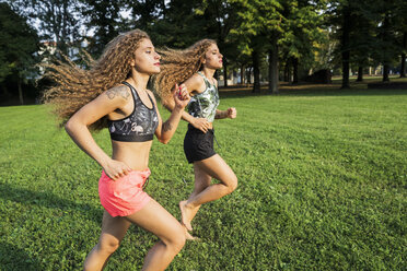 Twin sisters jogging barefoot in a park - GIOF04745