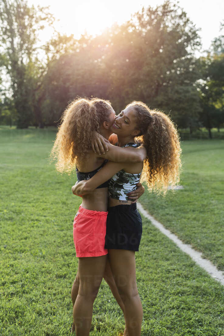 Twin sisters hugging each other in a park stock photo