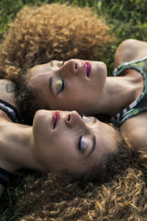 Porträt von rothaarigen Zwillingsschwestern, die nebeneinander auf einer Wiese liegen - GIOF04763