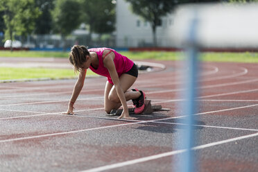 Female athlete taking position on her marks to start off the run