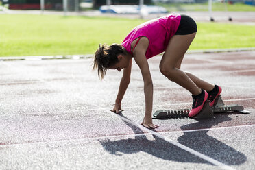 Female athlete taking position on her marks to start off the run