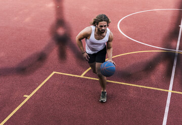 Junger Mann spielt Basketball auf einem Basketballplatz - UUF15554