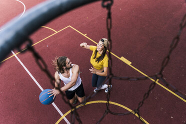 Young man and woman playing basketball on basketball ground - UUF15555