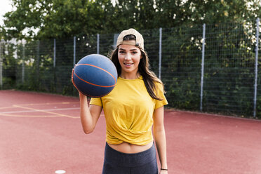 Glückliche junge Frau spielt Basketball - UUF15558