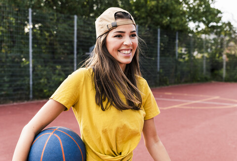 Glückliche junge Frau spielt Basketball, lizenzfreies Stockfoto