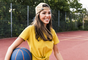 Happy young woman playing basketball - UUF15559