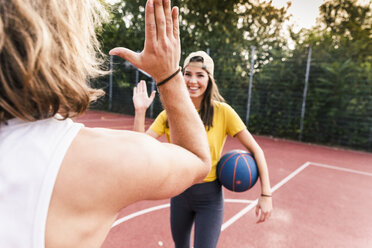 Junger Mann und junge Frau geben sich nach einem Basketballspiel die Hand - UUF15560