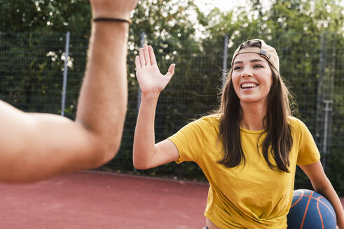 Junger Mann und junge Frau geben sich nach einem Basketballspiel die Hand - UUF15562
