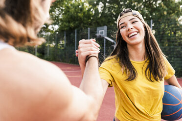 Junger Mann und junge Frau geben sich nach einem Basketballspiel die Hand - UUF15563