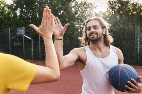 Junger Mann und junge Frau geben sich nach einem Basketballspiel die Hand, lizenzfreies Stockfoto