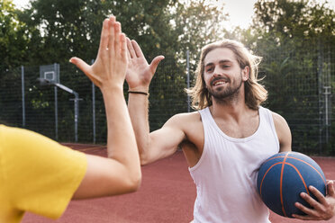 Junger Mann und junge Frau geben sich nach einem Basketballspiel die Hand - UUF15566