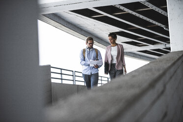 Junge Geschäftsleute diskutieren über das Dokument auf ihrem Weg zur Arbeit - UUF15600