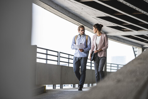 Junge Geschäftsleute diskutieren über das Dokument auf ihrem Weg zur Arbeit, lizenzfreies Stockfoto