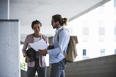 Junge Geschäftsleute diskutieren über das Dokument auf ihrem Weg zur Arbeit - UUF15603