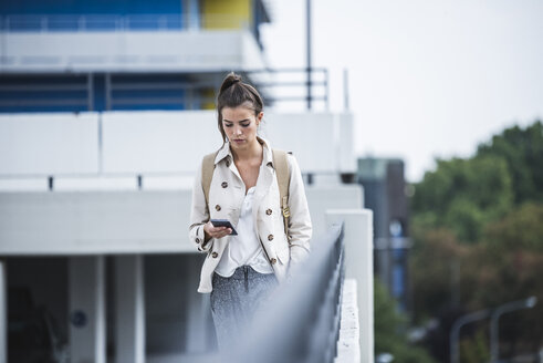 Junge Geschäftsfrau mit Smartphone in der Stadt - UUF15636