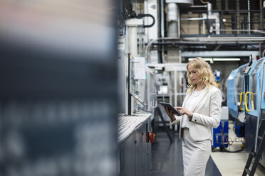 Frau benutzt Tablet an einer Maschine in einer Fabrikhalle - DIGF05294