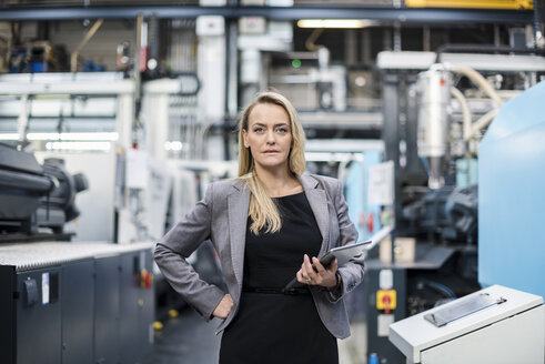 Portrait of confident woman holding tablet in factory shop floor - DIGF05304