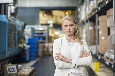 Portrait of confident woman in factory storehouse - DIGF05323