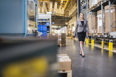 Woman with tablet walking in factory storehouse - DIGF05331