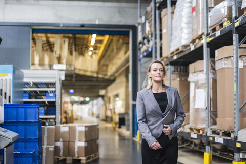 Porträt einer selbstbewussten Frau mit Tablet in einem Fabriklager, lizenzfreies Stockfoto