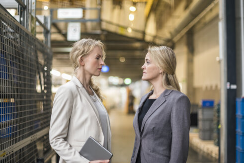 Zwei Frauen stehen sich in einem Fabriklager gegenüber - DIGF05337