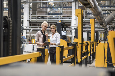 Zwei Frauen mit Tablet im Gespräch in einer Fabrikhalle - DIGF05350