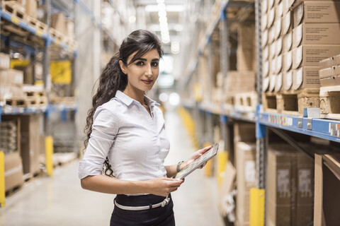 Portrait of confident woman holding tablet in factory storehouse stock photo