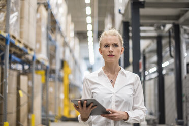 Portrait of woman holding tablet in factory storehouse - DIGF05370