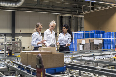 Drei Frauen diskutieren am Fließband in einer Fabrik - DIGF05373