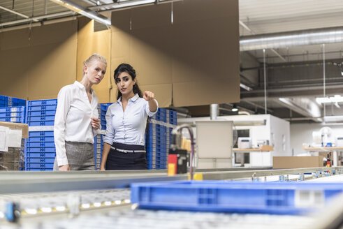 Zwei Frauen diskutieren am Fließband in einer Fabrik - DIGF05377