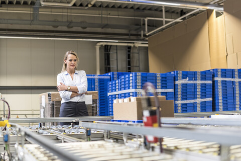 Frau schaut auf ein Förderband in einer Fabrik, lizenzfreies Stockfoto