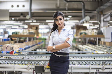 Portrait of confident woman at conveyor belt in factory - DIGF05380
