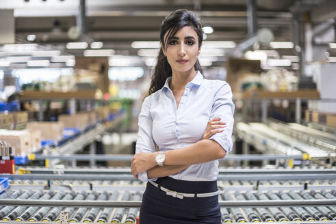Portrait of confident woman at conveyor belt in factory - DIGF05381
