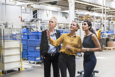 Three women talking in modern factory stock photo