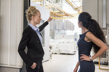 Zwei Frauen unterhalten sich in einer modernen Fabrik - DIGF05410