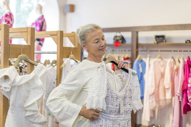 Lächelnde ältere Frau beim Einkaufen von Kleidung in einer Boutique - VGF00020