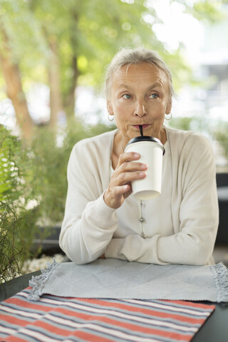 Ältere Frau mit einem Getränk in einem Straßencafé, lizenzfreies Stockfoto