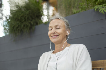 Lächelnde ältere Frau mit geschlossenen Augen und Kopfhörern im Freien - VGF00060