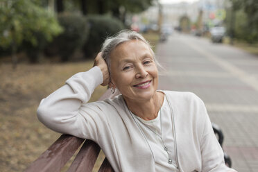 Porträt einer lächelnden älteren Frau, die sich auf einer Bank ausruht - VGF00063
