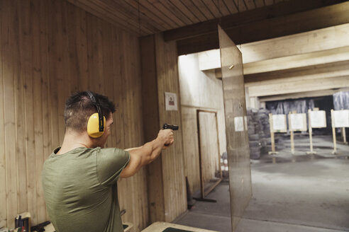 Mann, der mit einer Pistole in einer Schießhalle zielt - KKAF02582