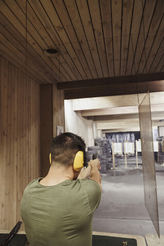Mann, der mit einer Pistole in einer Schießhalle zielt, lizenzfreies Stockfoto