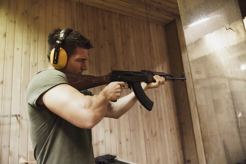 Mann zielt mit einem Gewehr in einer Indoor-Schießanlage - KKAF02588